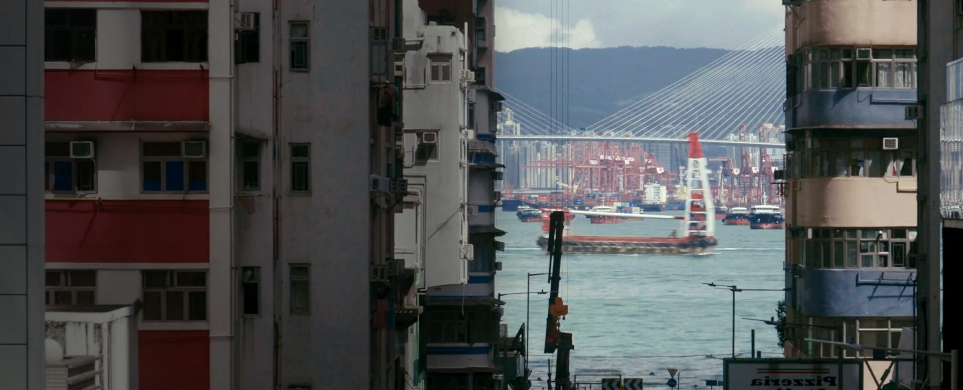 Hafen mit Frachtschiffen durch die Lücke von Hausreihen ersichtlich