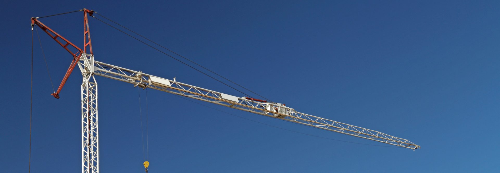 The image shows a construction crane against a clear blue sky.