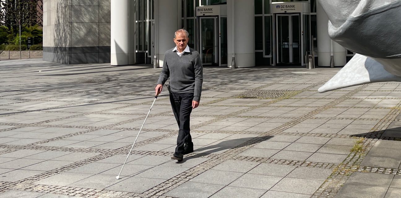 Rainer Krauser vor dem Gebäude der DZ Bank: Mit dem Blindenstock ertastet er den Weg. 