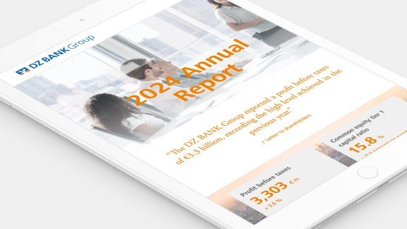 The image shows a tablet screen displaying a page titled **"2024 Annual Report"** from **DZ BANK Group**. The page contains:

1. **Header Details**:
   - **DZ BANK Group Logo**

2. **Main Content**:
   - **Title**: "2024 Annual Report"
   - A quote or statement likely describing the financial success or strategic moves of DZ BANK Group.

3. **Statistics Presented**:
   - **People Reached**: "3,303 Km"
   - **Generating Activity**: "15.8"

4. **Background Image**:
   - Featuring people presumably in a professional setting, suggesting a corporate office environment.

The layout and design suggest an emphasis on financial performance and corporate strategy, aimed at stakeholders and shareholders interested in the bank's annual performance.