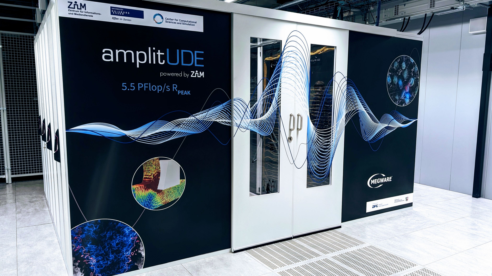 The image shows a large computer server or supercomputer enclosed in a white and black enclosure. The enclosure features the branding 'amplitUDE' powered by ZAM, advertising '5.5 PFLOPS@Rmax' along with scientific wave graphics and logos for ZAM and other scientific organizations. The scene is in a modern, clean facility, likely a data center or computing laboratory.