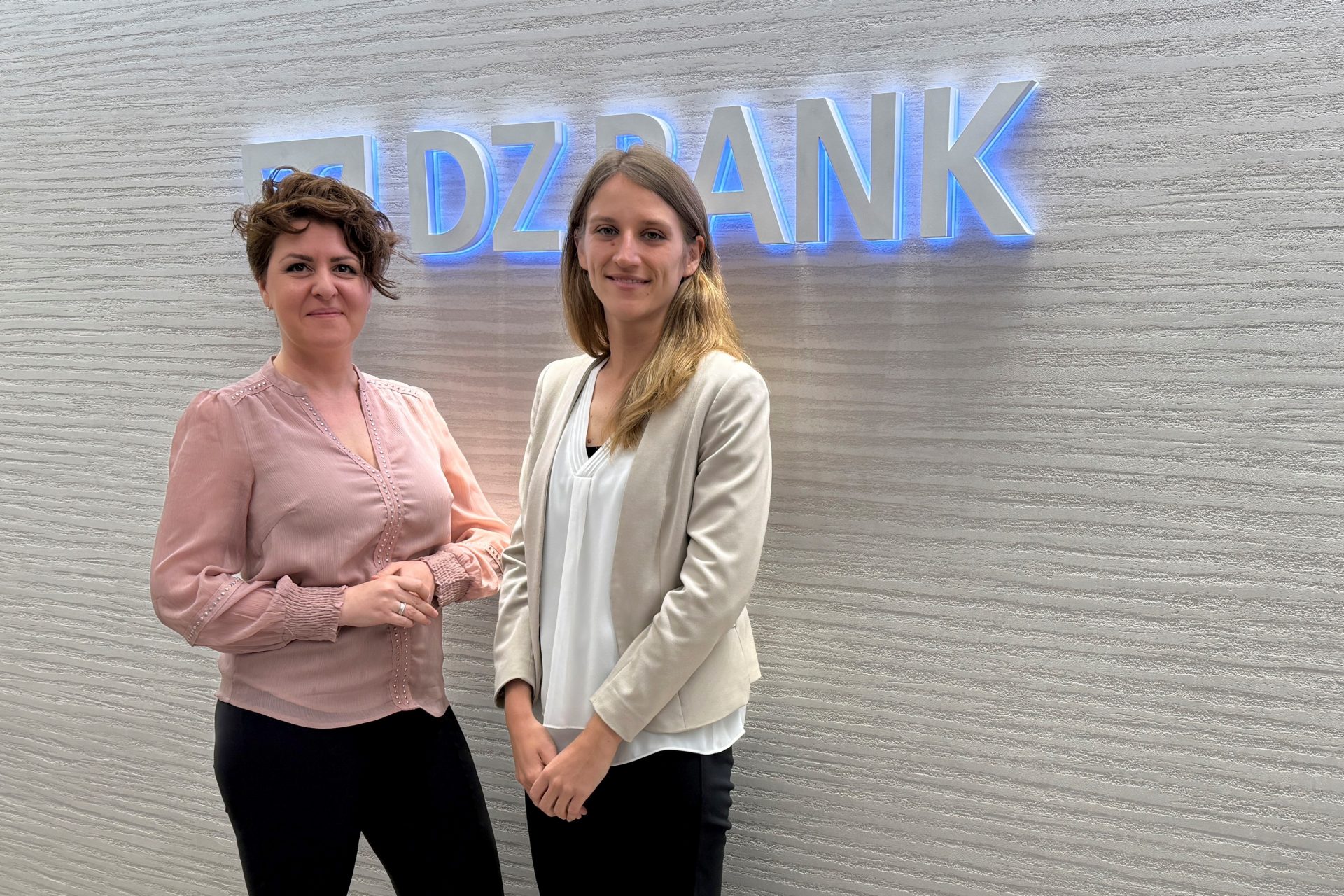 Two DZ BANK team members under the logo and word mark of DZ BANK