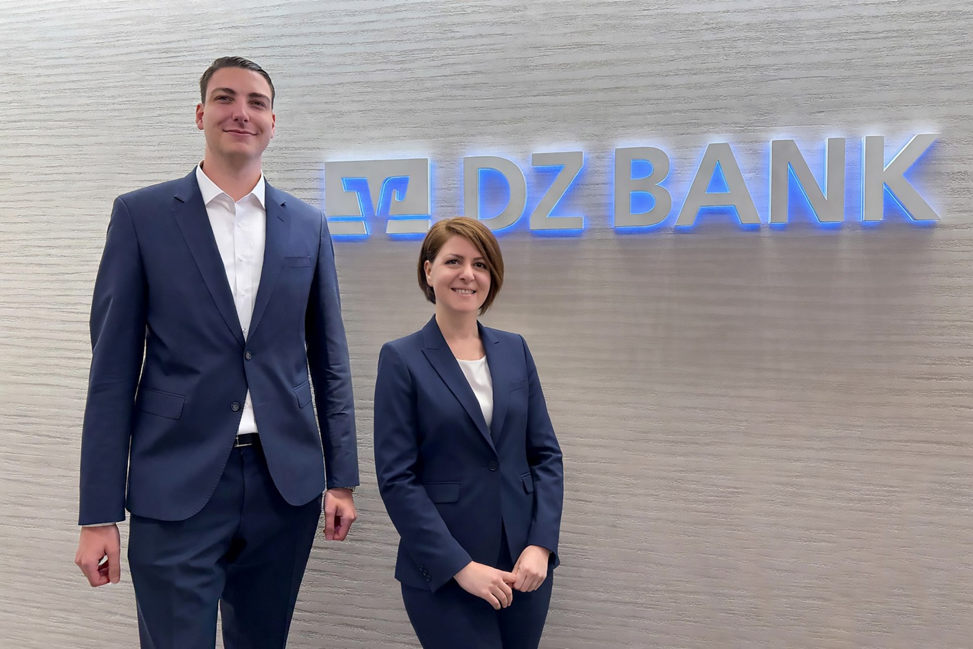 Two DZ BANK team members under the logo and word mark of DZ BANK