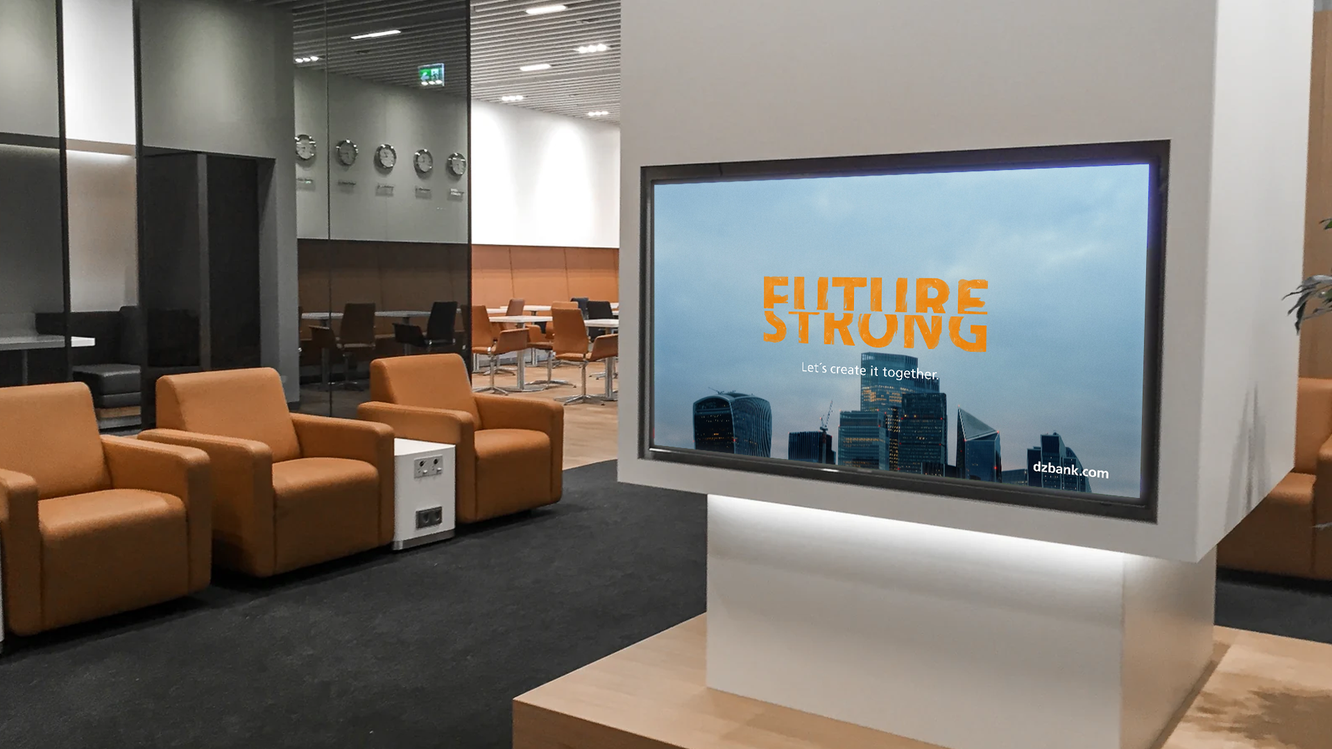 The image depicts a sleek and modern corporate office environment. Here's a breakdown of what's in the image:
1. **Office Space:**
- The image shows a modern office or business lounge area that has a professional and clean aesthetic.
- There are glass partitions that separate different sections of the office.
2. **Furnishings:**
- There are comfortable tan leather armchairs arranged on a black carpeted section of the floor, suggesting a waiting or relaxation area.
- It's likely that this arrangement is aimed at providing comfort to visitors or employees.
3. **Television Monitor:**
- A large monitor is prominently displayed on a white stand.
- The screen displays the words "FUTURE STRONG" in bright orange lettering.
- The background of the text is a city skyline, highlighting modern urban architecture.
4. **General Atmosphere:**
- The image portrays a modern business environment that focuses on technology and a forward-thinking mentality.
- The slogan "FUTURE STRONG" suggests a company or brand with an emphasis on progress, innovation, and resilience.
5. **Ambient Lighting:**
- The lighting appears to be well-designed, likely using overhead lights that contribute to the professional feel of the space.
6. **Additional Details:**
- In the background, there's a glimpse of an office setup with desks and chairs, indicating a workspace.
- A few decorations or details on the walls observe the brand aesthetics or personal touches which give this space a polished and refined appearance.
Overall, the image represents a modern, professional, and inviting office environment, showcasing comfort, design, and a strong emphasis on future-forward thinking.
---