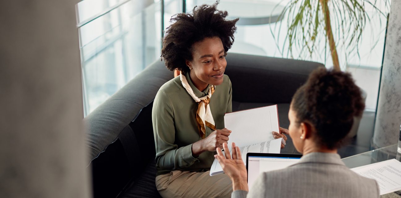 Two women in business attire confering